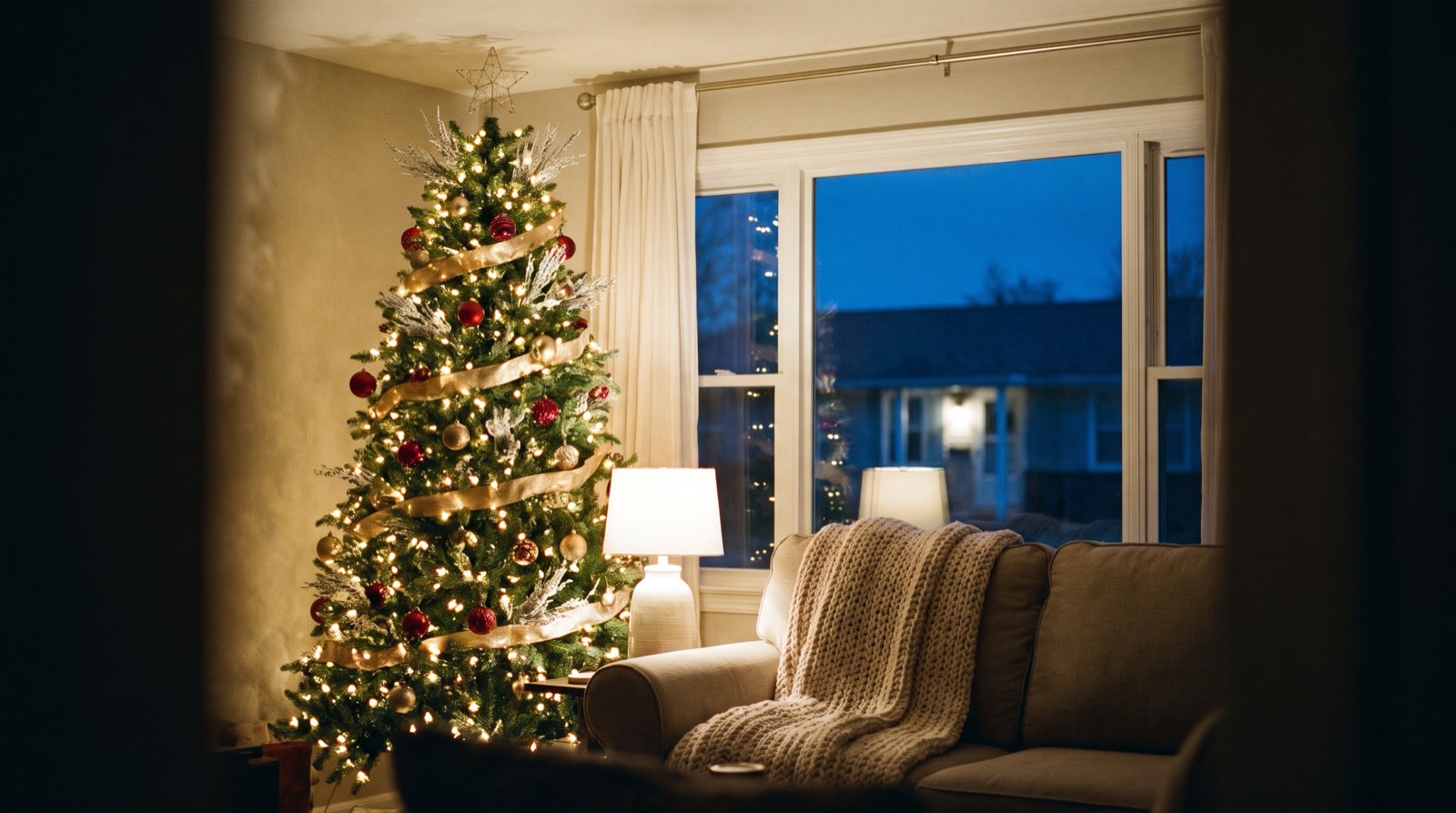 A finished Christmas tree glowing in an ordinary living room at dusk